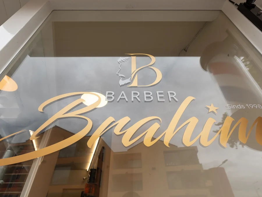 Het logo van Barber Brahim op de etalageruit