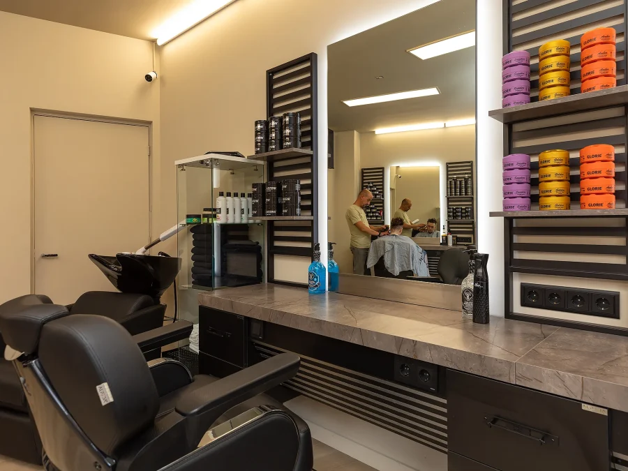 Haarproducten op de kaptafel, met een barbier aan het werk op de achtergrond