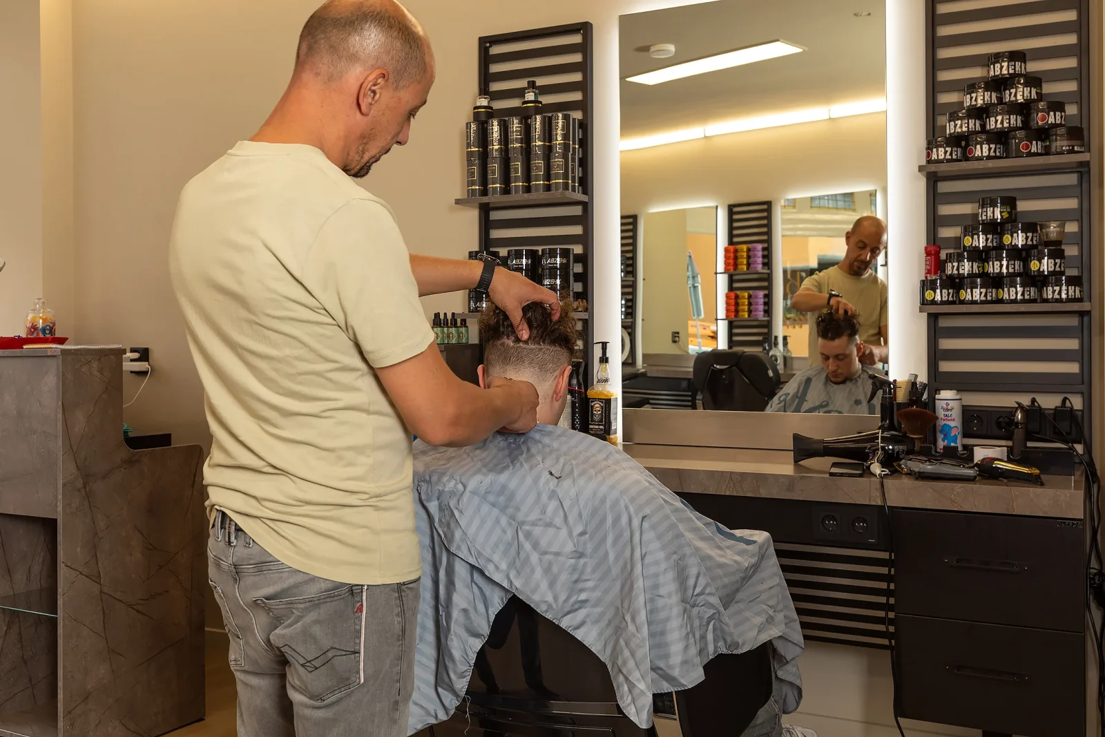 Een barbier knipt geconcentreerd het haar van een klant