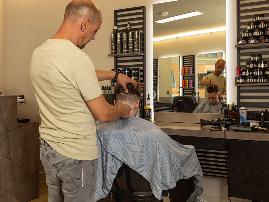 Een barbier knipt geconcentreerd het haar van een klant
