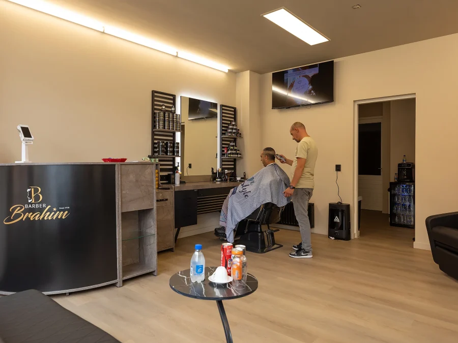 De balie van Barber Brahim met het logo, met een knipbeurt op de achtergrond